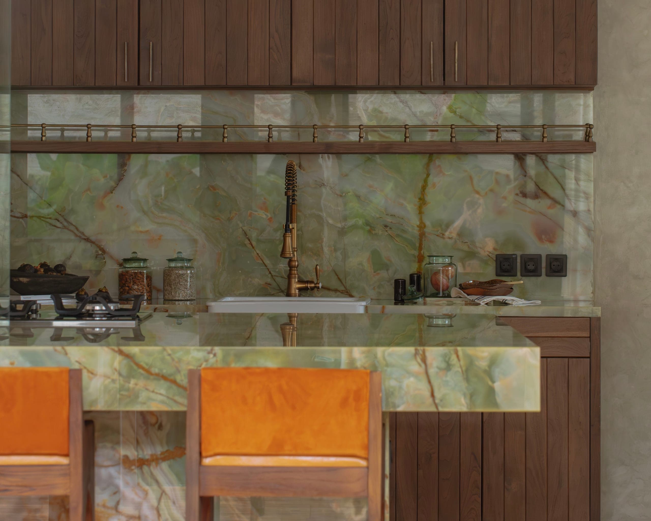 A custom kitchen detail, green onyx splashback and counter against dark walnut cabinetry
